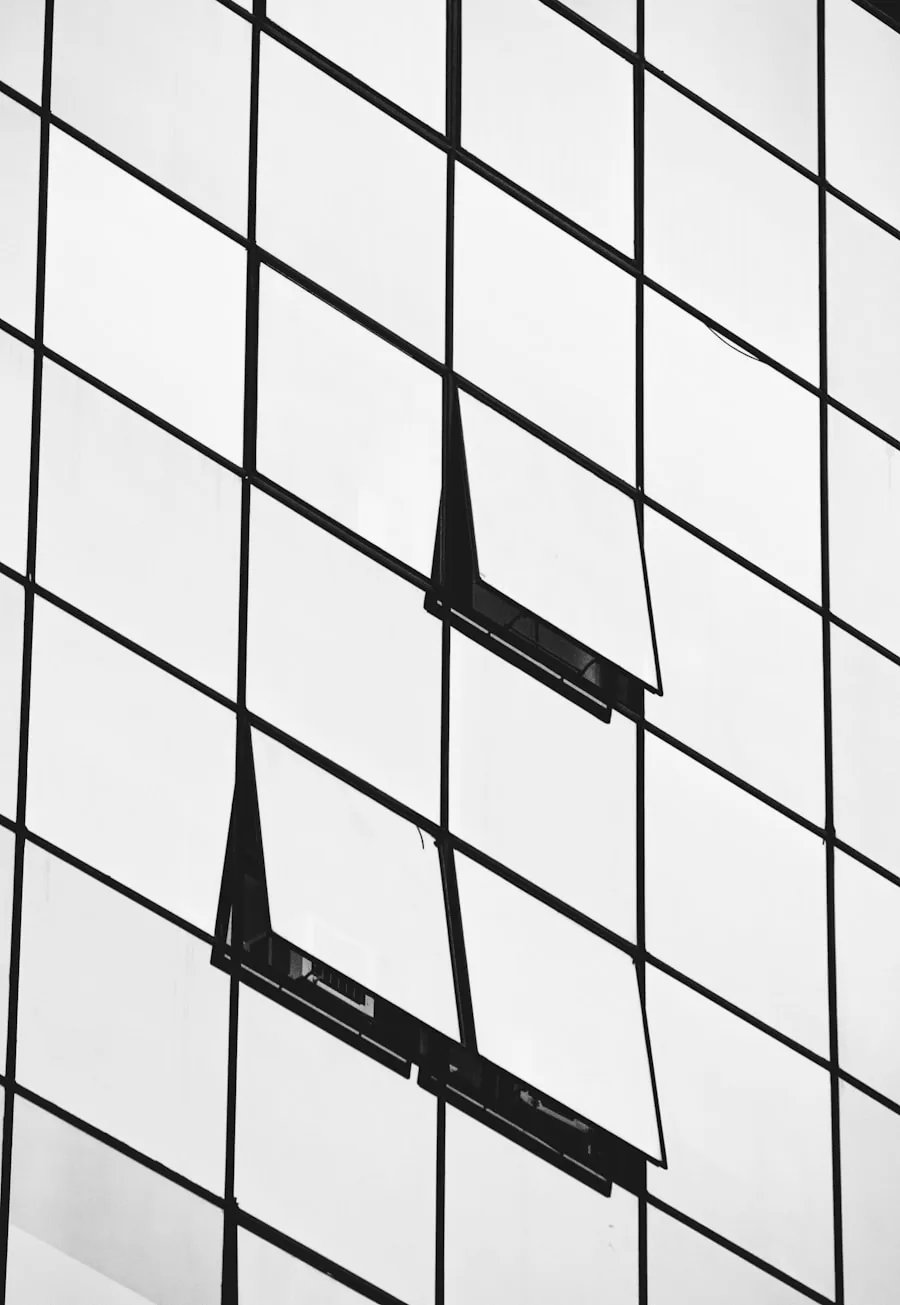 Close-up of a glass office facade, two windows tilted open in the grid