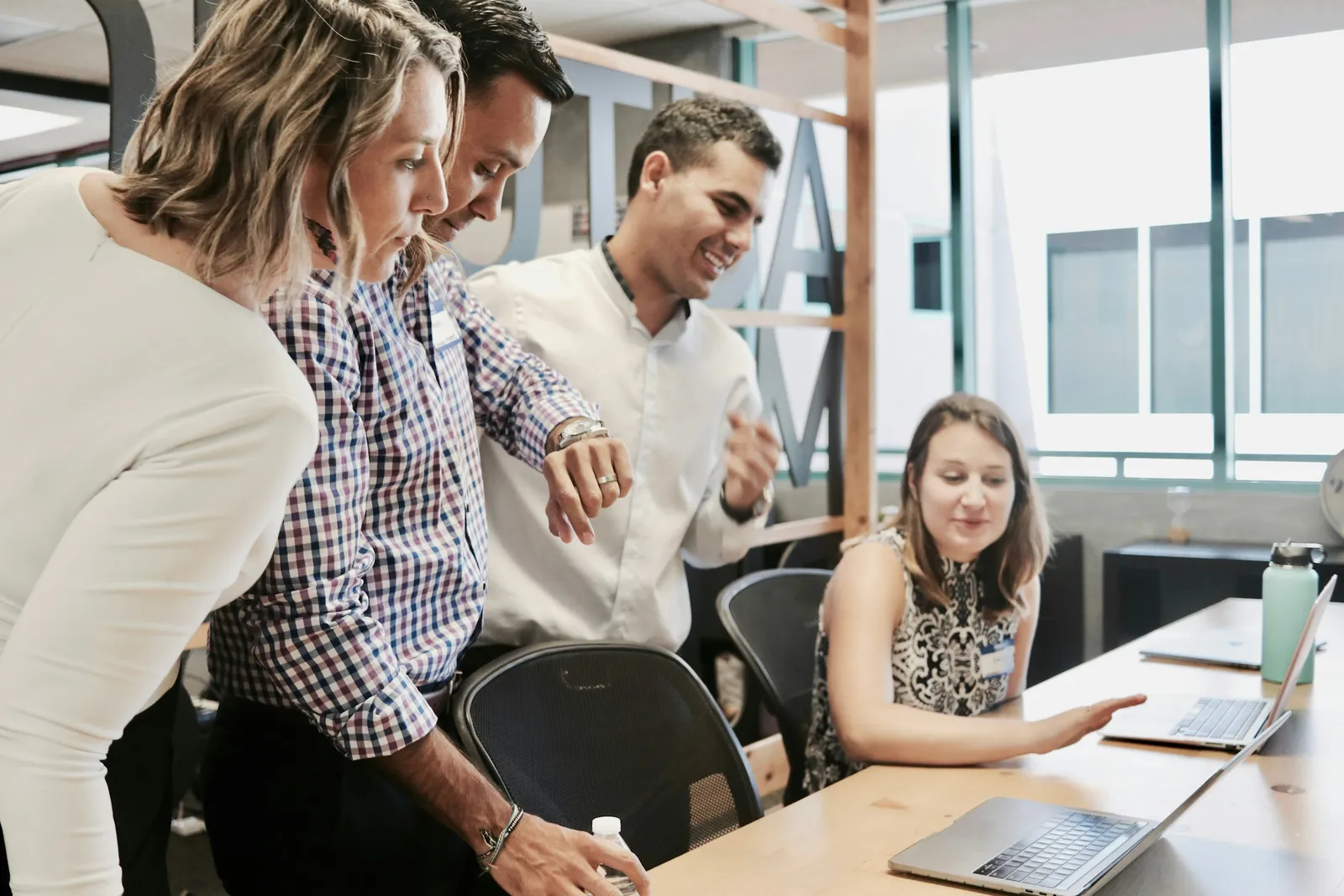 A small team gathered around a laptop in a shared workspace, working through a task together